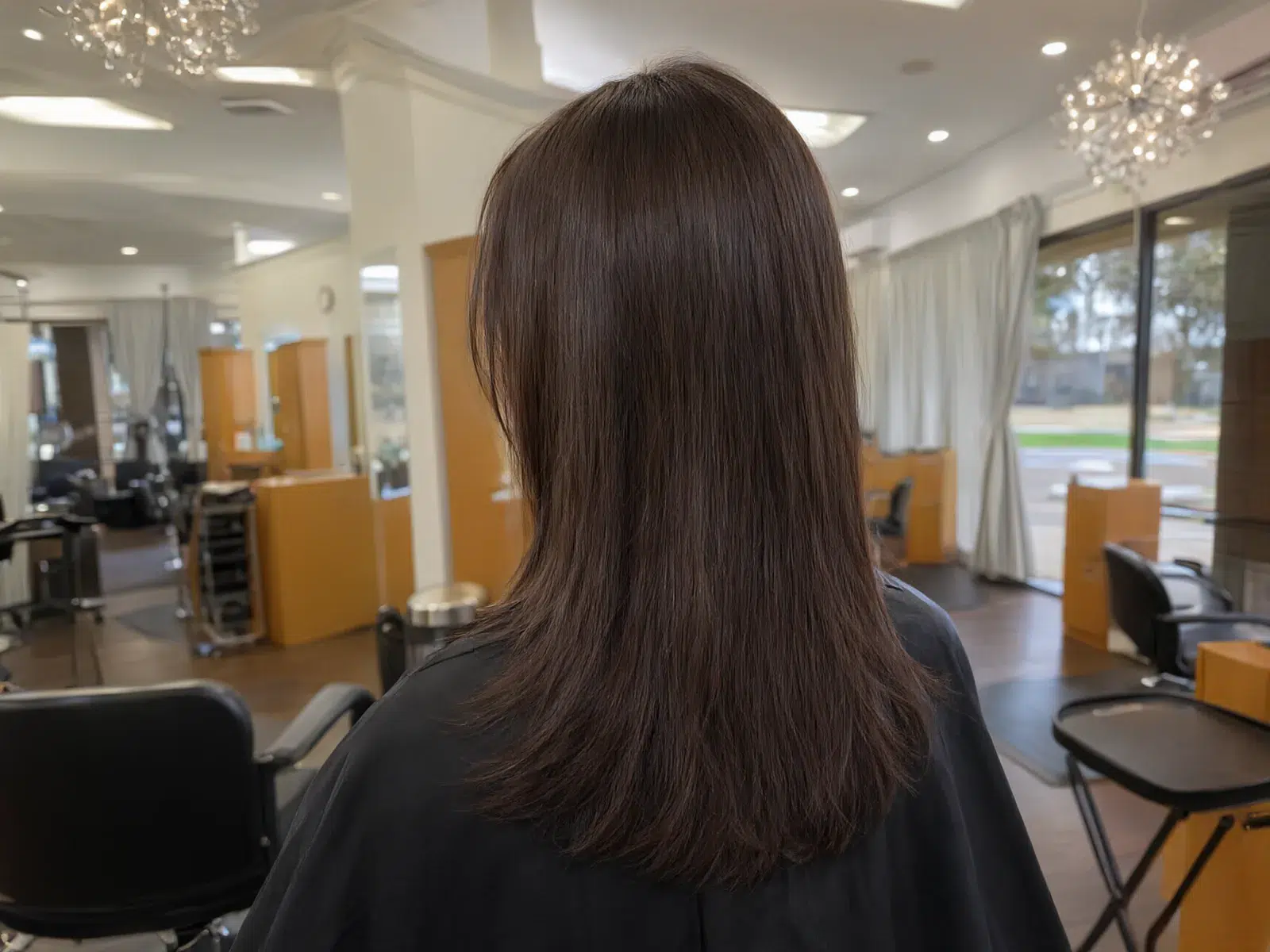 Close-up: straight, sleek, glass-smooth brunette hair after a keratin treatment