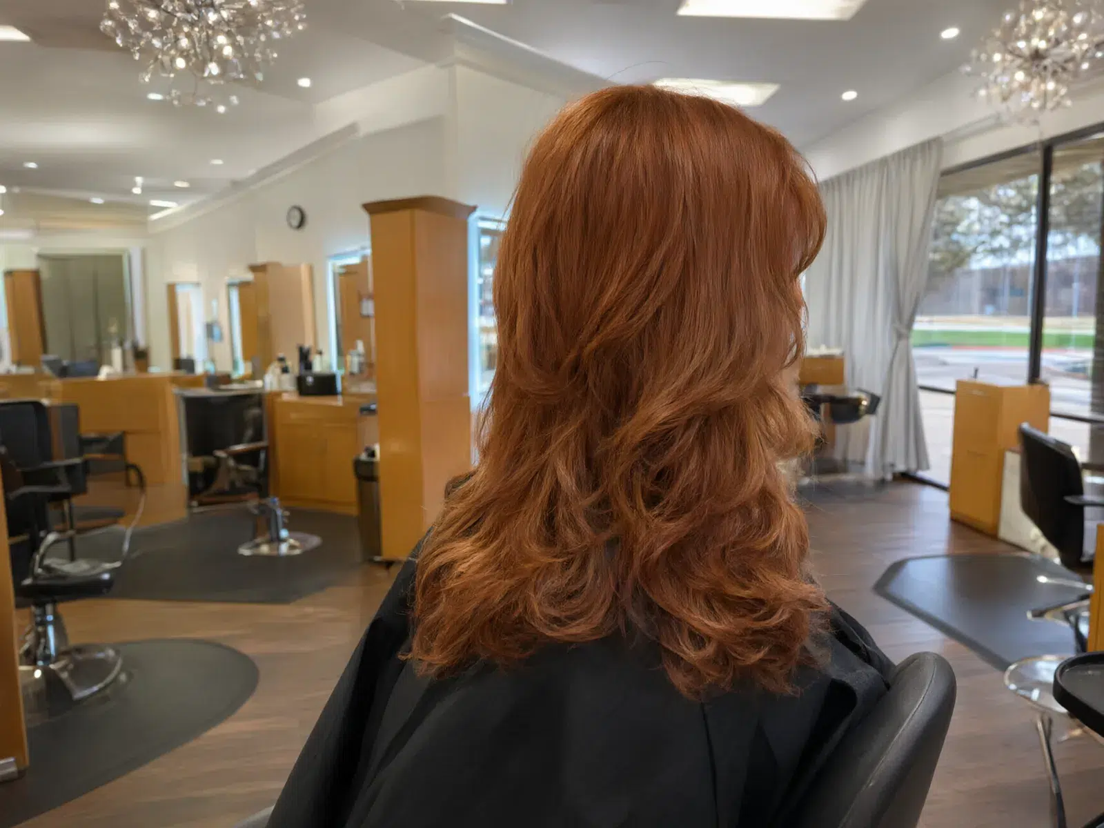 Long copper-red hair with glossy curls, in the salon chair at Salon D