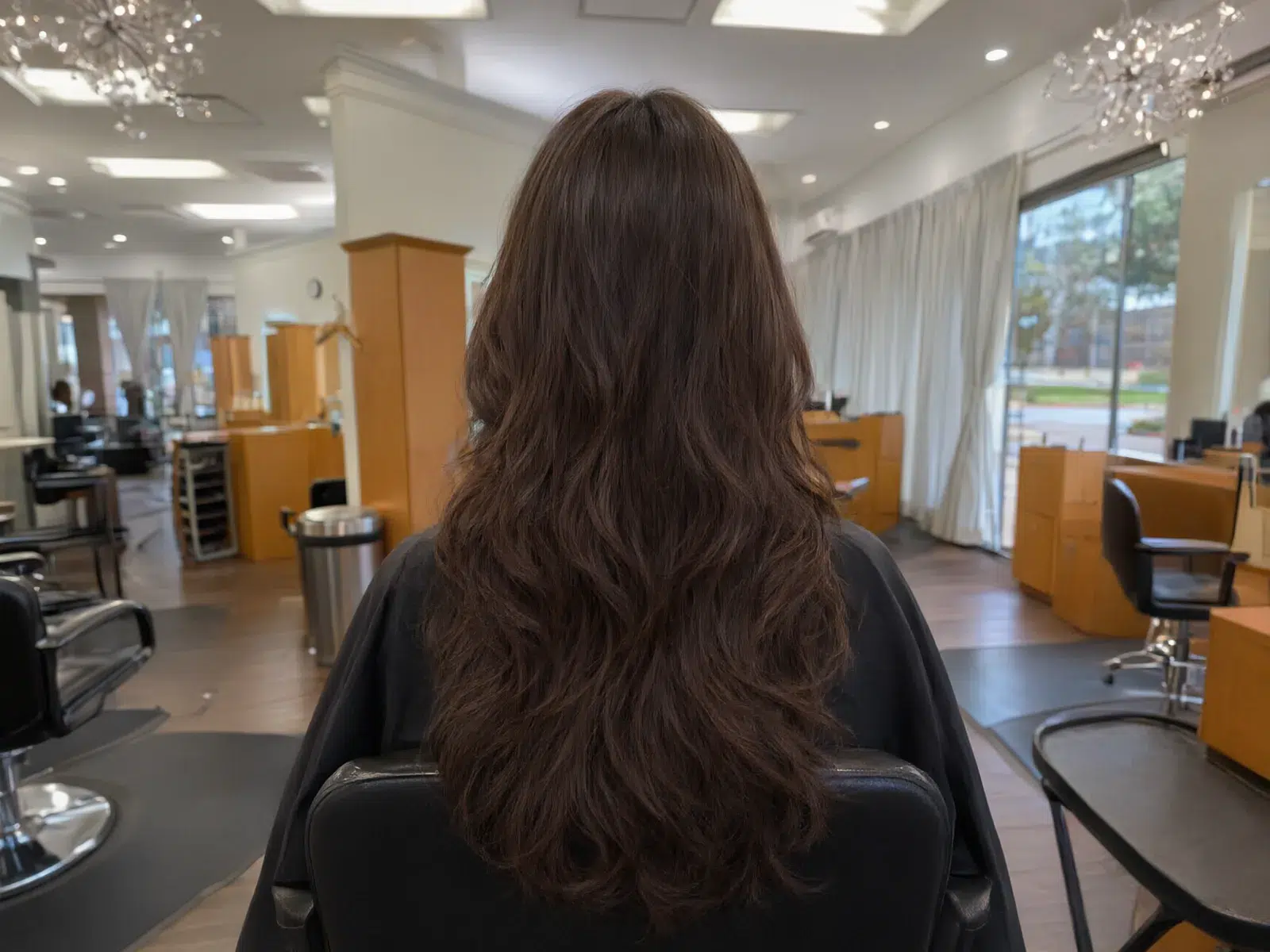 Long, full hair extensions blended seamlessly, soft waves, in the salon chair at Salon D