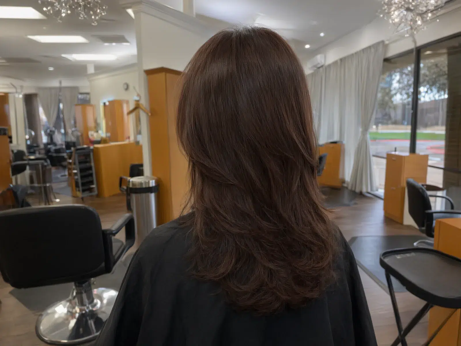 Rich glossy brunette hair color with soft dimension, in the salon chair at Salon D