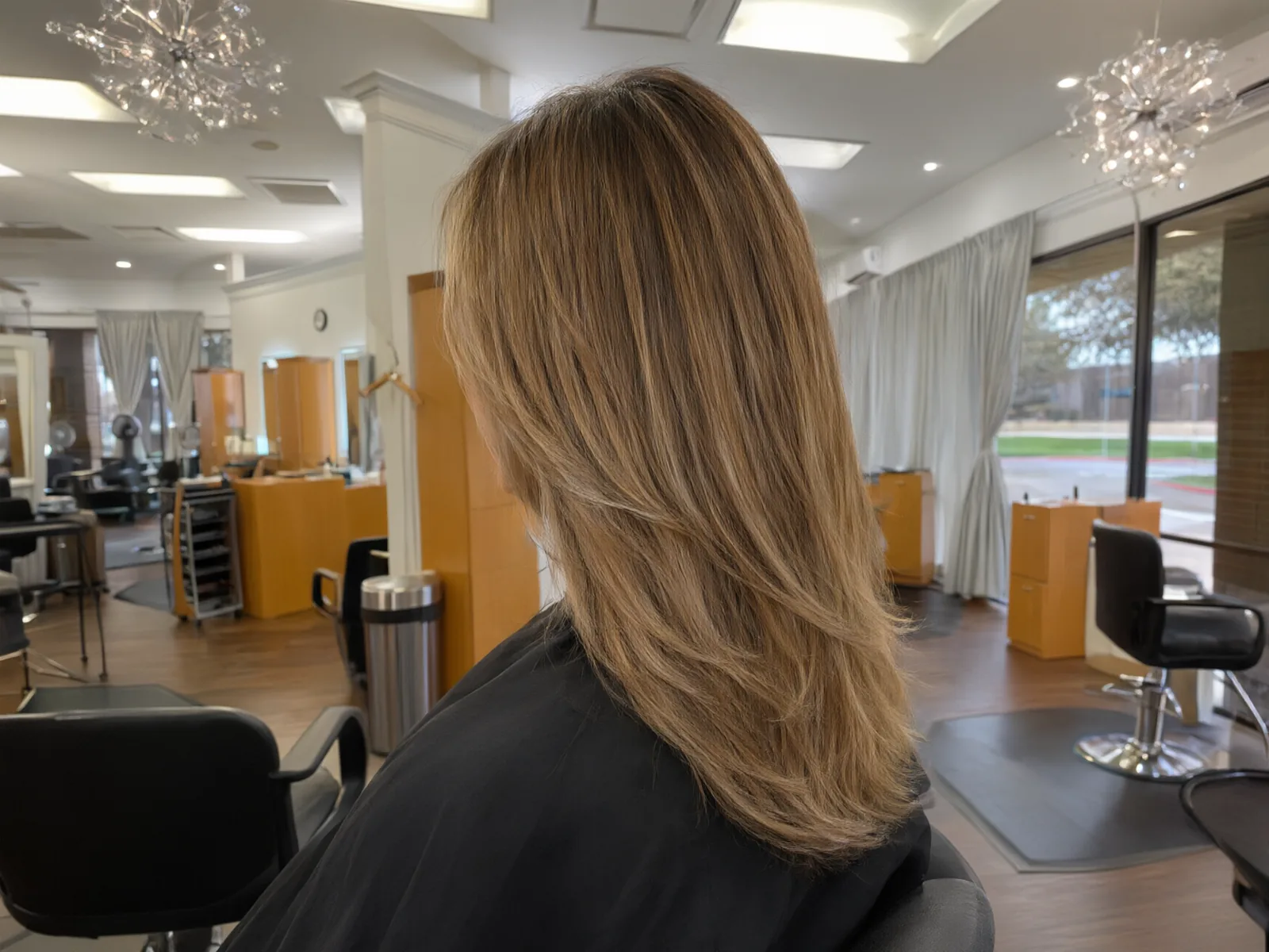 Soft hand-painted balayage in honey and caramel tones, blended at the roots, in the salon chair at Salon D