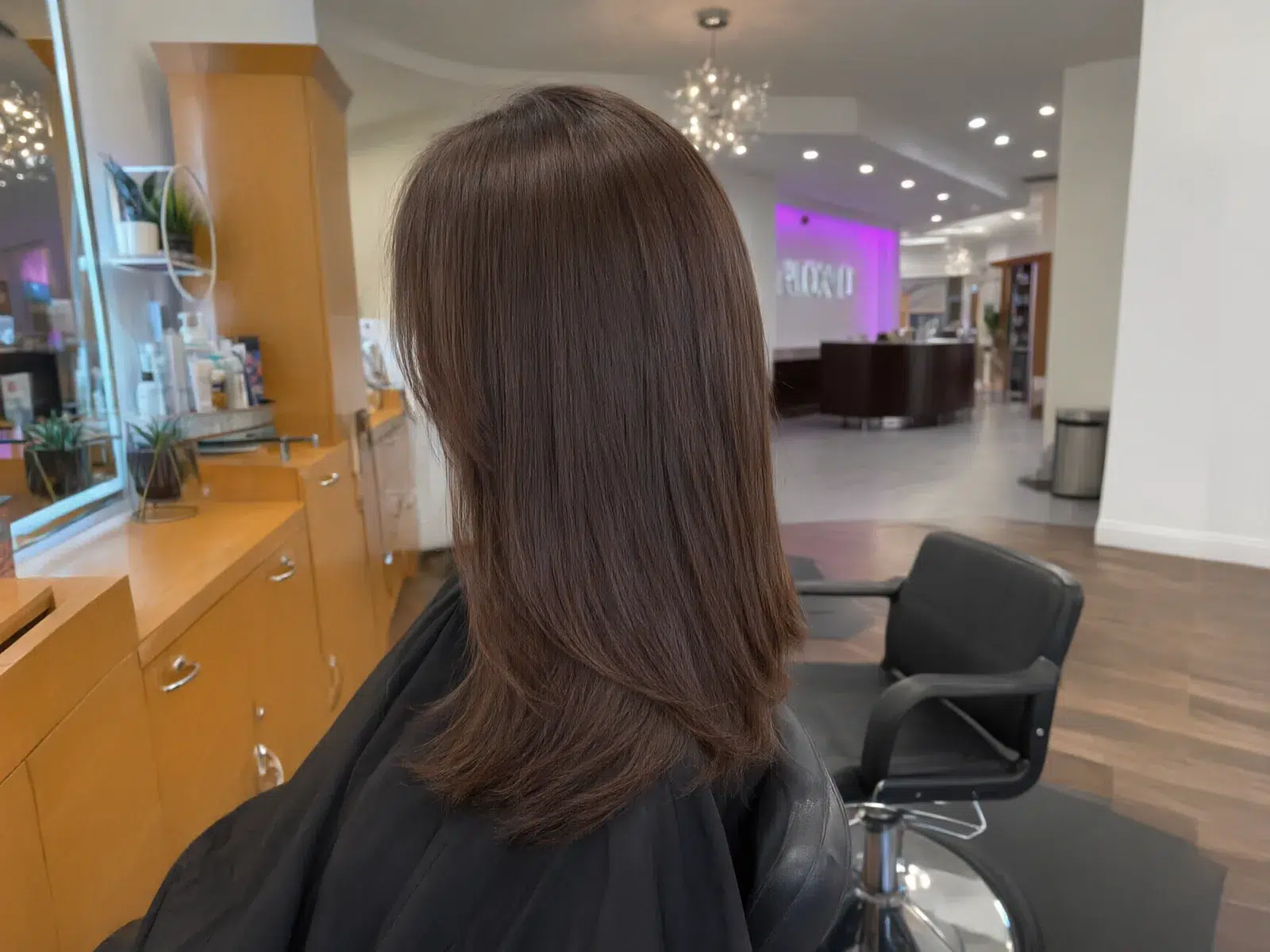 Straight, sleek, glass-smooth brunette hair after a keratin treatment, in the salon chair at Salon D