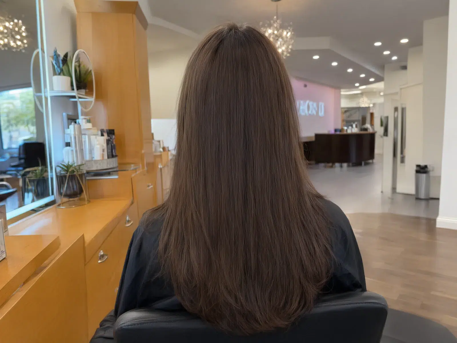Straight, sleek, glass-smooth brunette hair after a keratin treatment, in the salon chair at Salon D