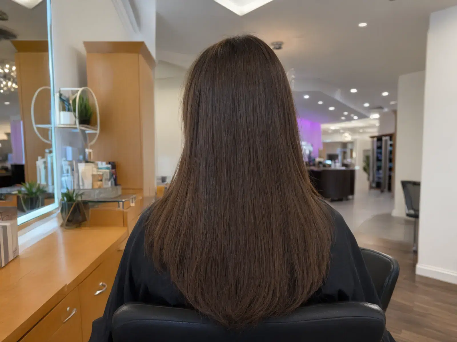 Straight, sleek, glass-smooth brunette hair after a keratin treatment, in the salon chair at Salon D
