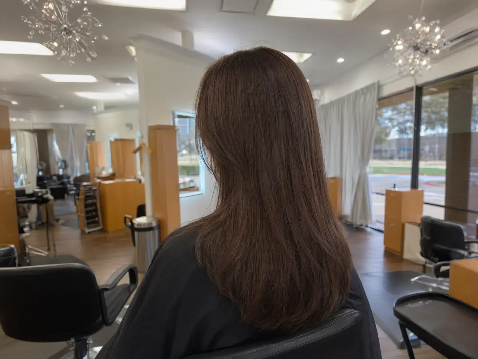Straight, sleek, glass-smooth brunette hair after a keratin treatment, in the salon chair at Salon D