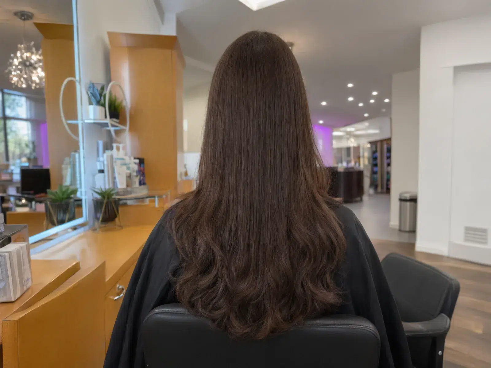 Straight, sleek, glass-smooth brunette hair after a keratin treatment, in the salon chair at Salon D