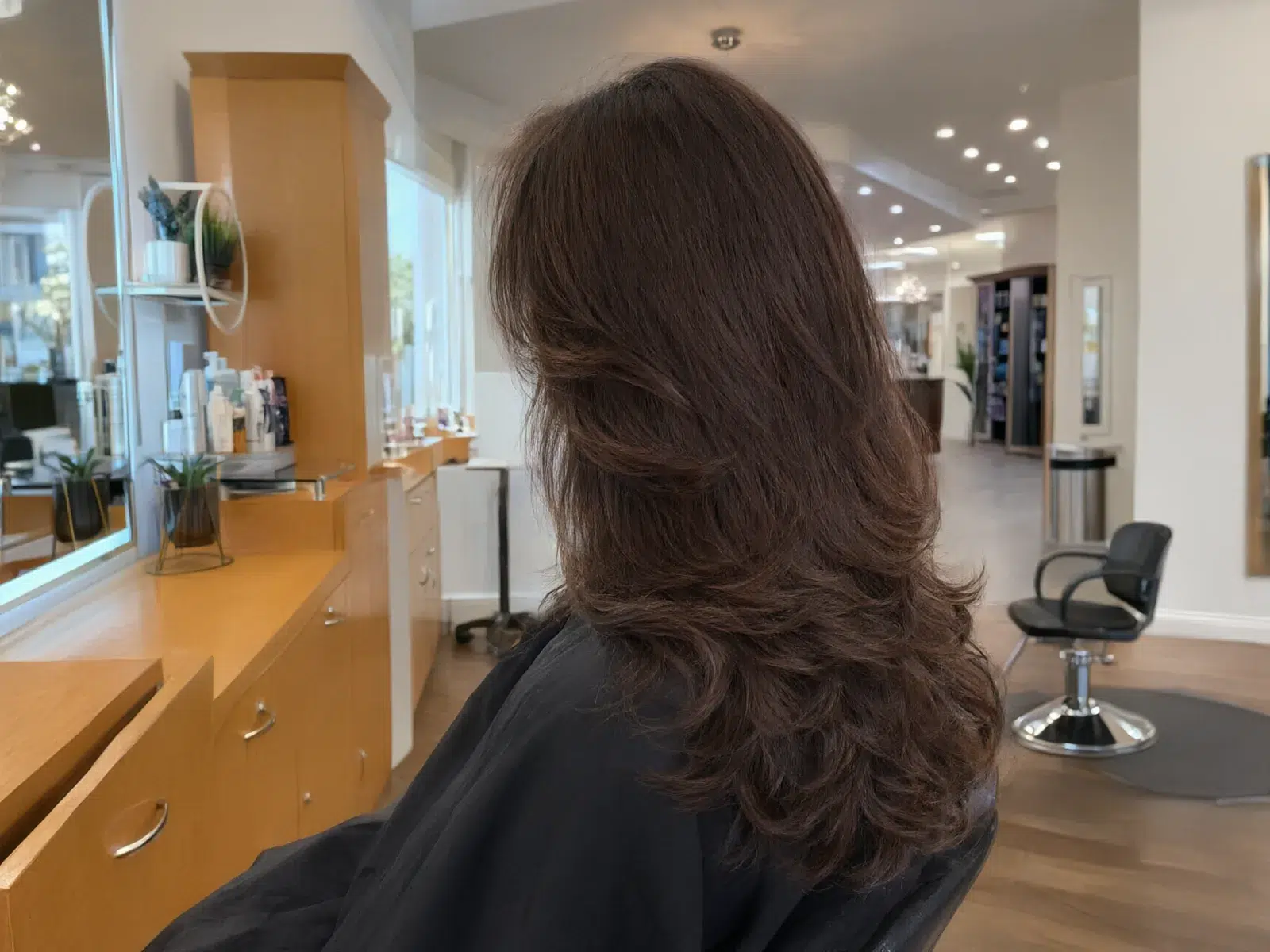 Voluminous espresso-brown blowout with bouncy ends, in the salon chair at Salon D